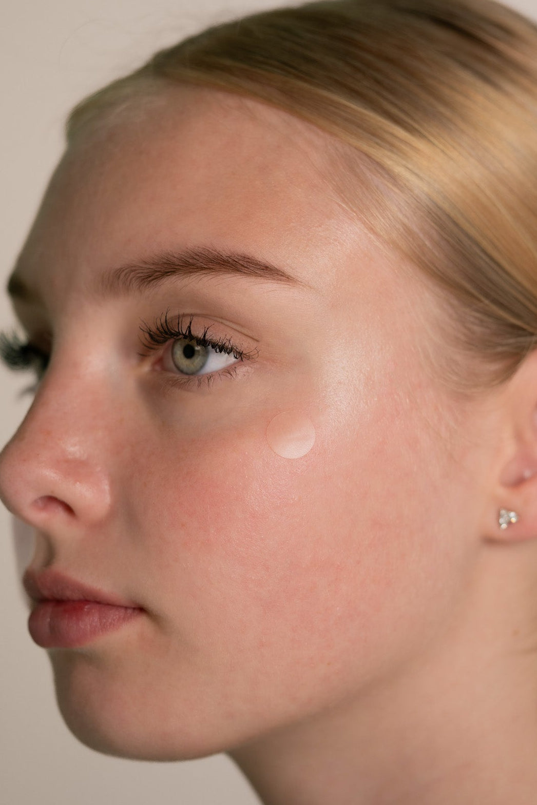 Close-up of a person wearing a small earring with a neutral background