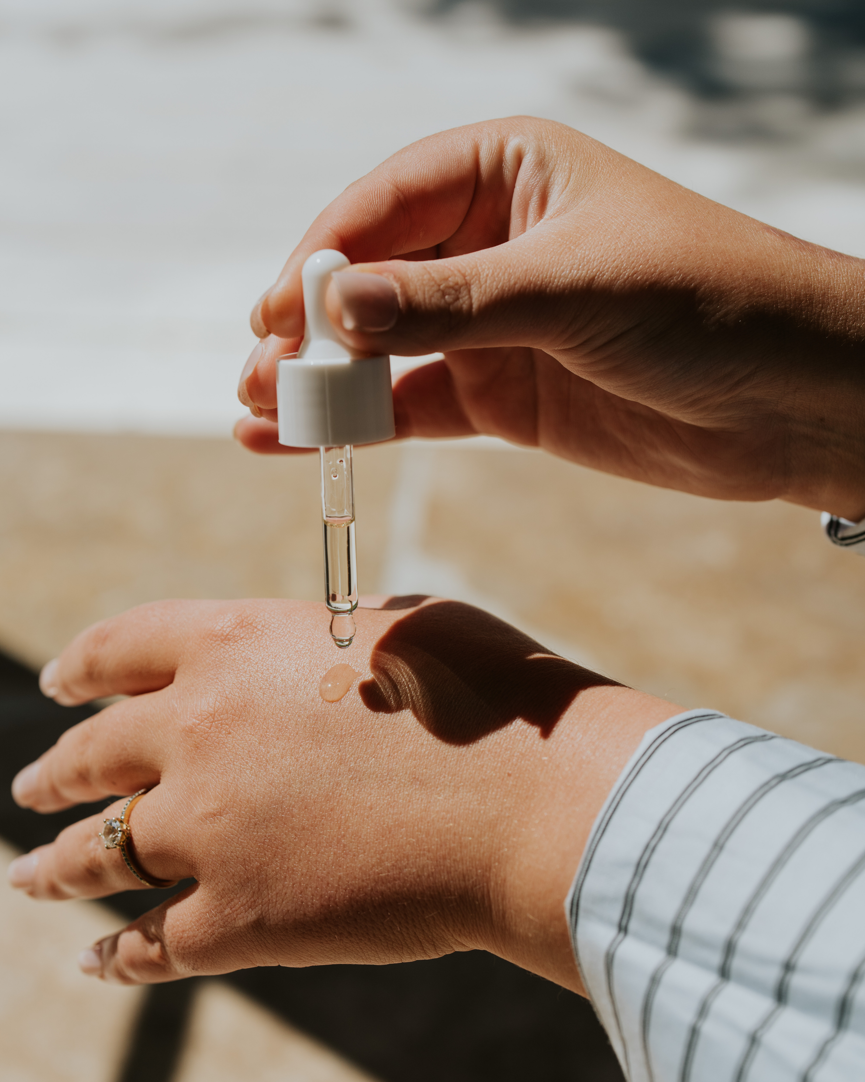 Person applying a dropper of liquid to their wrist outdoors