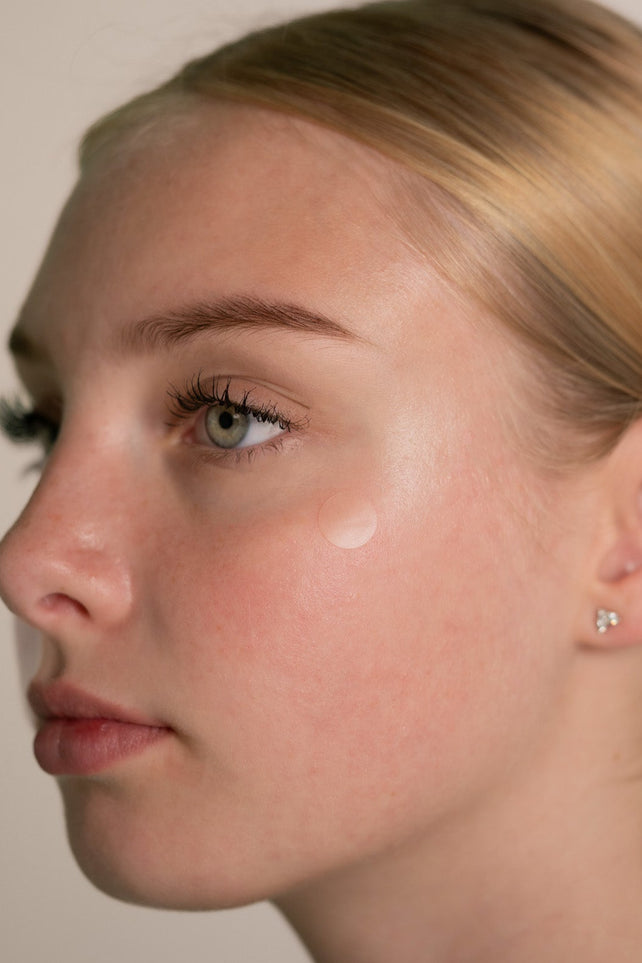 Close-up of a person wearing a small earring with a neutral background